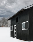 A wintery scene of a charcoal barn surrounded by snow in Woodstock Vermont