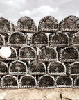 A pile of metallic lobster pots stacked on each other on a stone surface by the water in St Andrews, Scotland