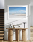 Modern interior with a wooden console table, lamp, and framed beach scene on the wall.
