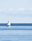 A single sailboat on the blue open ocean with a clear sky above taken on the Nantucket sound