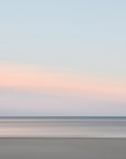 This image presents a soft and serene artwork capturing the essence of a sunset over Harwich Port, Cape Cod. The artwork features a minimalist design with a subtle blend of warm orange and pink hues on the horizon, gradually fading into cooler shades of blue and gray as the eye moves upward.