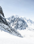 An aerial view of the French Alps covered in snow, with clouds in the sky.