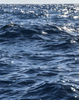 This image features a captivating photograph titled "Deep Waters," showcasing the serene and expansive Nantucket Sound. The composition captures the calming effect of the ocean waves, highlighted by the gentle sparkle of sunlight reflecting off the water's surface.