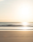 Sunset over a calm sea with golden undertones and a blurred foreground