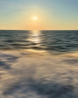 A scenic view of the ocean with a golden sunset glow, reflecting on the water surface.