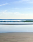 An abstract and scenic view of the ocean with blue waves crashing onto the golden sand beach.