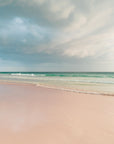 Dramatic beach scene with pink sands, green waters and cloudy sky