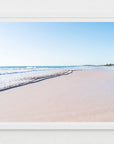 Framed photograph of a secluded beach with clear blue sky, blue ocean waves and pink sandy beach