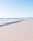 Secluded beach with clear blue sky, ocean waves and deserted pink sands
