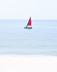 Sailboat with a red sail on a calm blue ocean