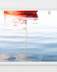 Framed photograph of a red boat reflected in water