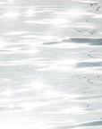 Ripples on a reflective and sparkling grey ocean.