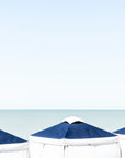 Naples,Florida Three vibrant beach cabanas stand against a quiet horizon of sea and sky, creating a minimalist.