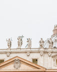 Facade of a basilica with statues and a dome at the Vatican in Rome, Italy