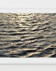 This image features a captivating photograph titled "Water Glow," showcasing the serene and expansive Atlantic Ocean. The artwork captures the texture and subtle colors of the ocean surface, enhanced by a soft, golden light that Imparts a tranquil and almost ethereal quality to the scene.