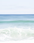 This image displays a fine art photograph titled "Shades of Blue," featuring a serene beach scene. The artwork captures the calming effect of blue and turquoise ocean waves against a broad expanse of sky.