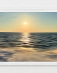 A scenic view of the ocean with a golden sunset glow, reflecting on the water surface.