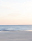 An abstract photograph of a soft and serene beach scene with a calm ocean, clear sky and blue, beige and pink tones