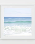 This image displays a fine art photograph titled "Shades of Blue," featuring a serene beach scene. The artwork captures the calming effect of blue and turquoise ocean waves against a broad expanse of sky.