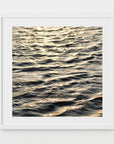 This image features a captivating photograph titled "Water Glow," showcasing the serene and expansive Atlantic Ocean. The artwork captures the texture and subtle colors of the ocean surface, enhanced by a soft, golden light that Imparts a tranquil and almost ethereal quality to the scene.