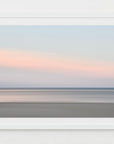 This image presents a soft and serene artwork capturing the essence of a sunset over Harwich Port, Cape Cod. The artwork features a minimalist design with a subtle blend of warm orange and pink hues on the horizon, gradually fading into cooler shades of blue and gray as the eye moves upward.
