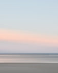 This image presents a soft and serene artwork capturing the essence of a sunset over Harwich Port, Cape Cod. The artwork features a minimalist design with a subtle blend of warm orange and pink hues on the horizon, gradually fading into cooler shades of blue and gray as the eye moves upward.