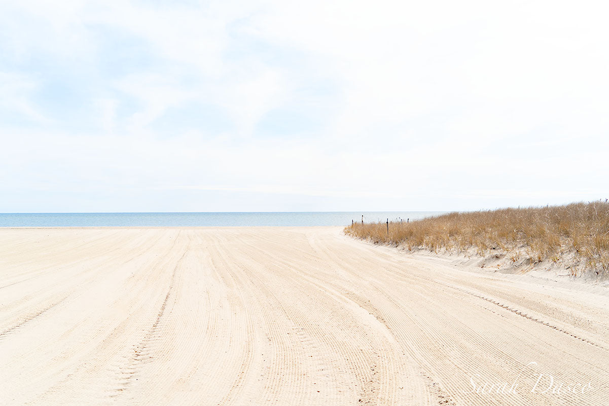 Beach landscape with sand dunes,  clear sky, blue water and yellow sand