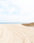 Beach landscape with sand dunes,  clear sky, blue water and yellow sand