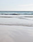 A serene abstract beach scene with gentle waves and a clear sky. Soft blue, grey, pink and beige under tones