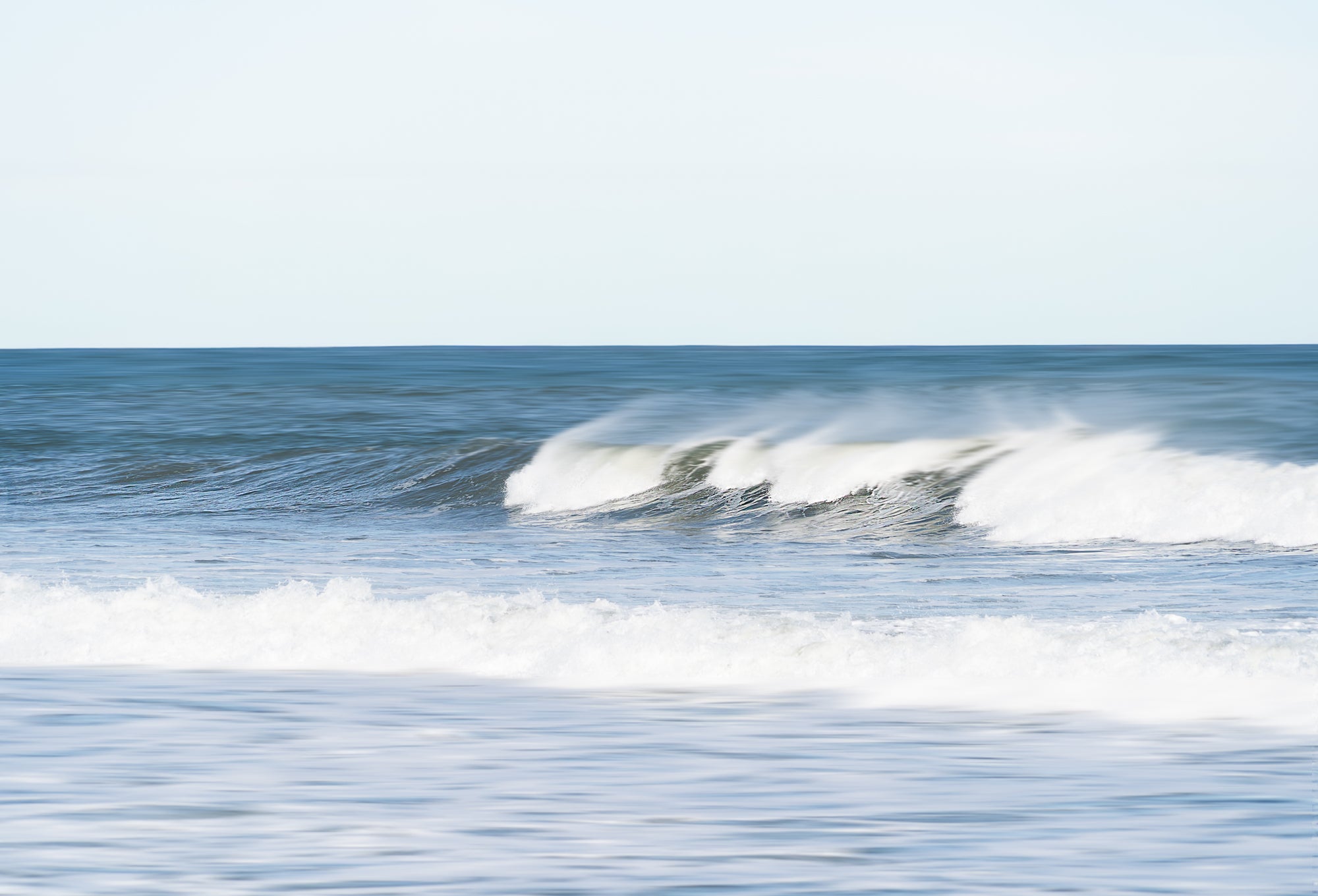 Ocean waves crashing on a beach with a clear sky