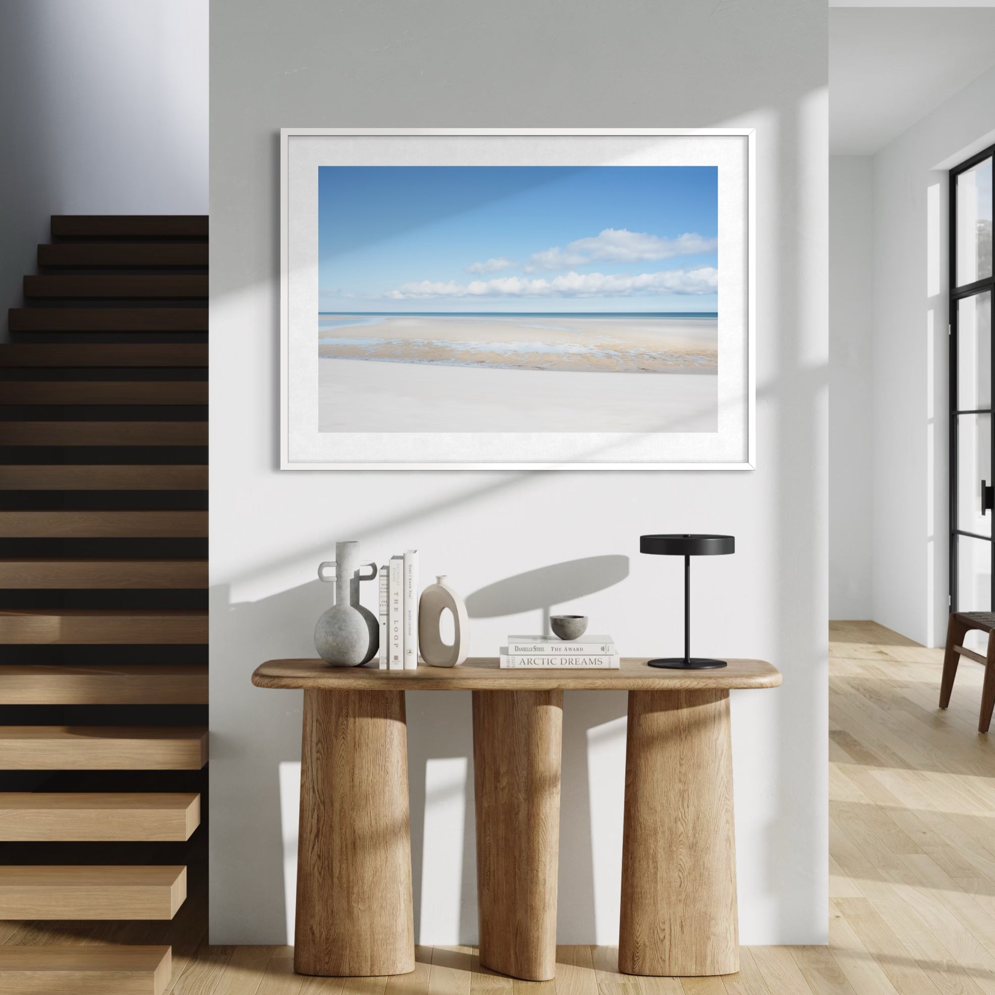 Modern interior with a wooden console table, lamp, and framed beach scene on the wall.