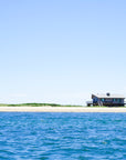 Small house on a sandy island with blue water and clear sky