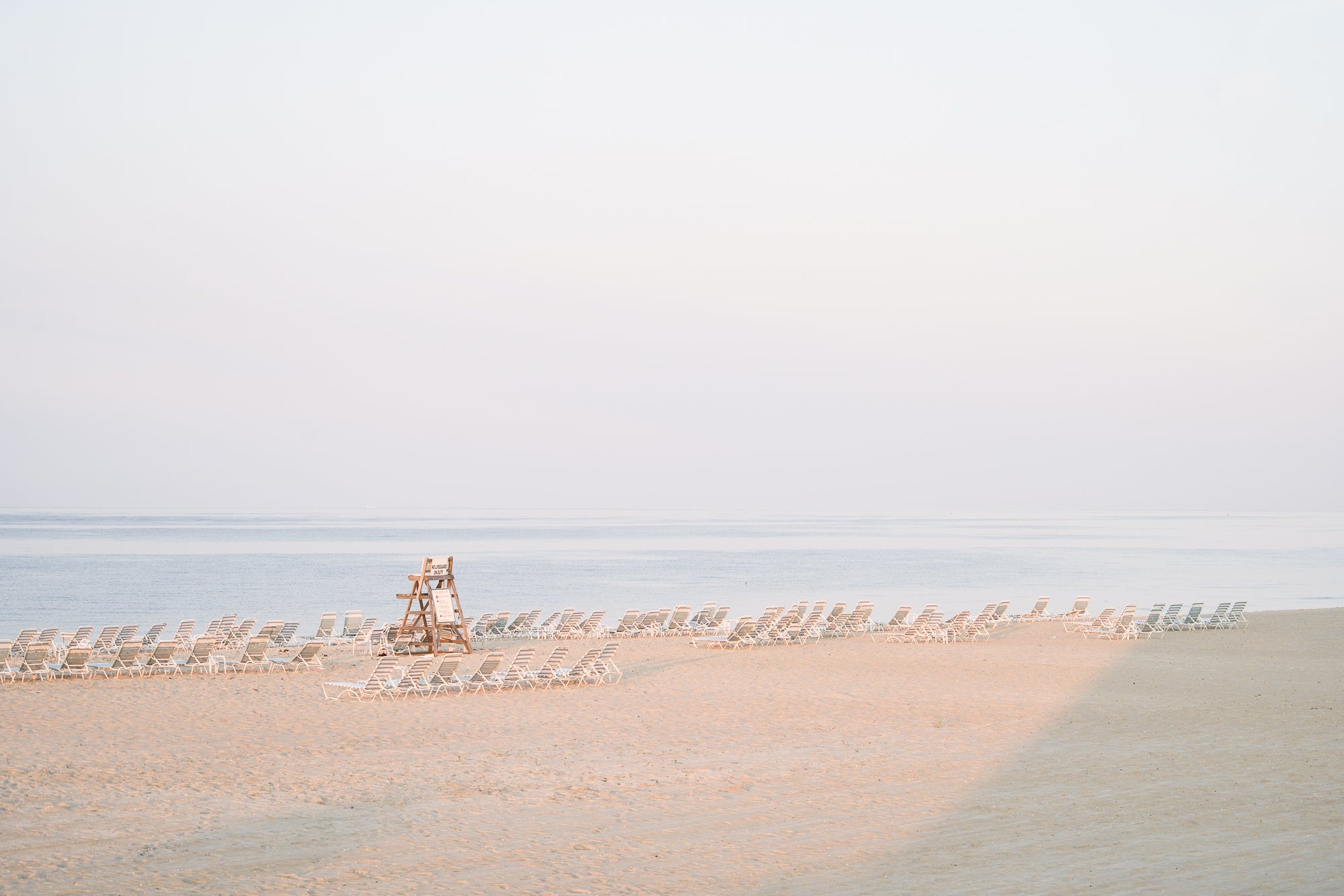 Minimal beach scene with a lifeguard chair with beach chairs 