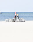 Life guard chair on a sandy beach with clear blue sky and ocean.