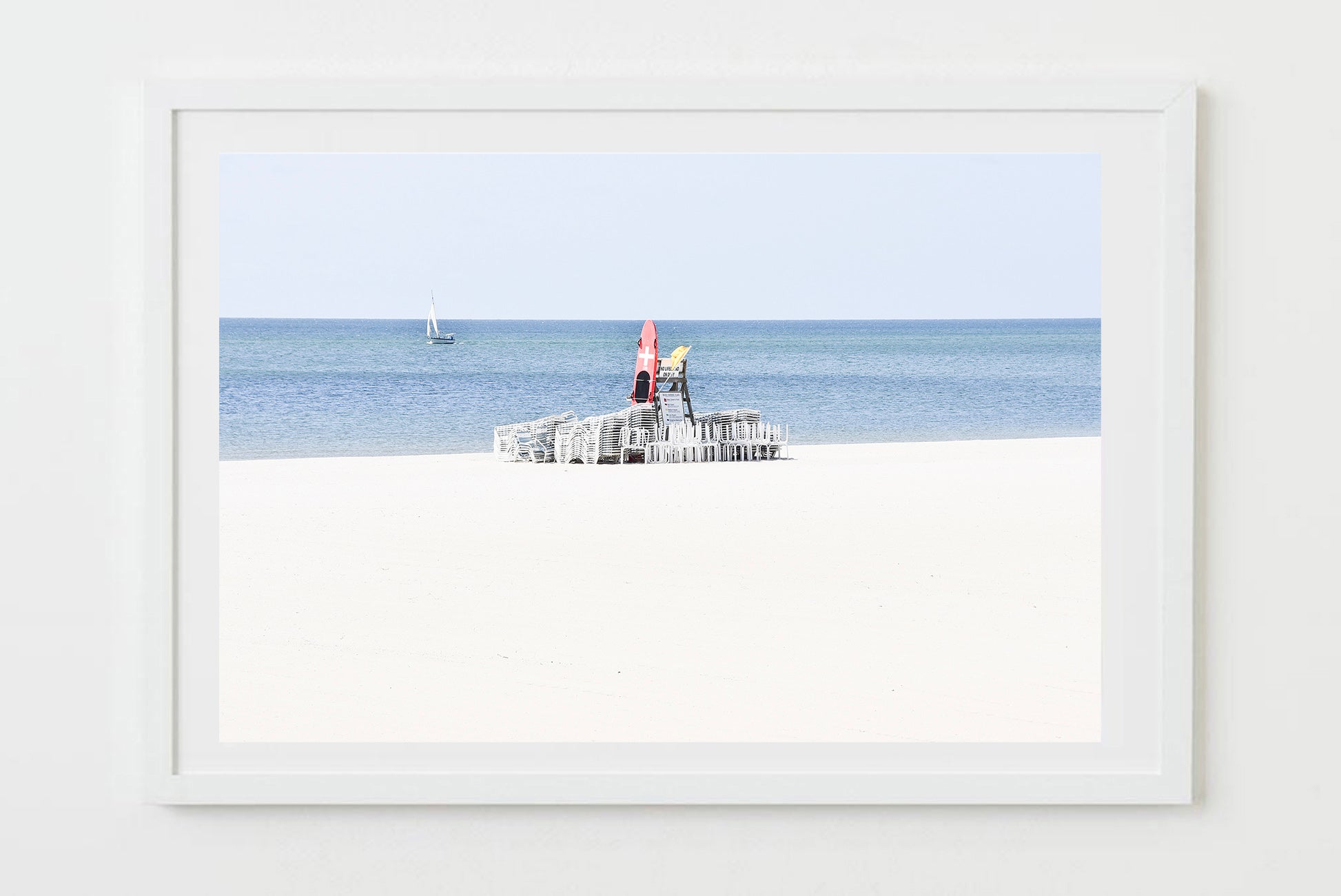 Framed artwork of a lifeguard chair on a beach with a white frame.