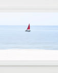 Framed artwork of a sailboat with a red sail on a blue background
